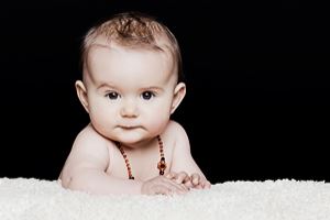 Baby liegt auf einem Fell und schaut in die Kamera