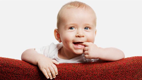 Babyfoto, aufgenommen im Fotostudio fröhliches Baby mit Finger im Mund