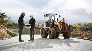 zwei Bauarbeiter und ein Radlader im Hintergrund