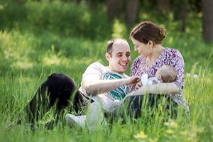 Pärchen mit Baby sitzt auf einer Wiese