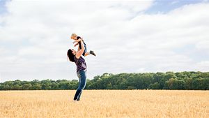 Mutter im Feld hält ihren Sohn in die Luft