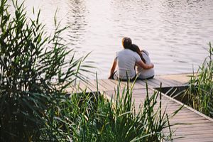 Paar sitzt am See auf einem Steg