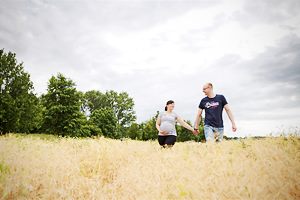 Pärchen mit Babybauch auf einem Feld